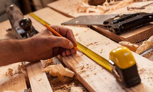 carpenter taking measurement of a wooden plank